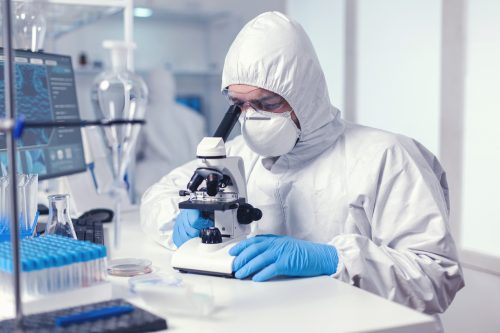 microbiologist with protection glasses using microscope dressed ppe suit scaled 1