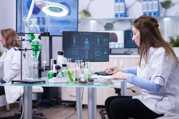 female scientist typing her computer data from last scientific tests chemistry lab scaled